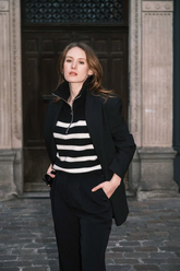 a lady in a striped zip up sweater, a black jacket and a pair of black pants